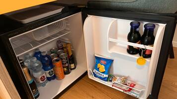 Un refrigerador compacto lleno de bebidas, aperitivos y salsas.