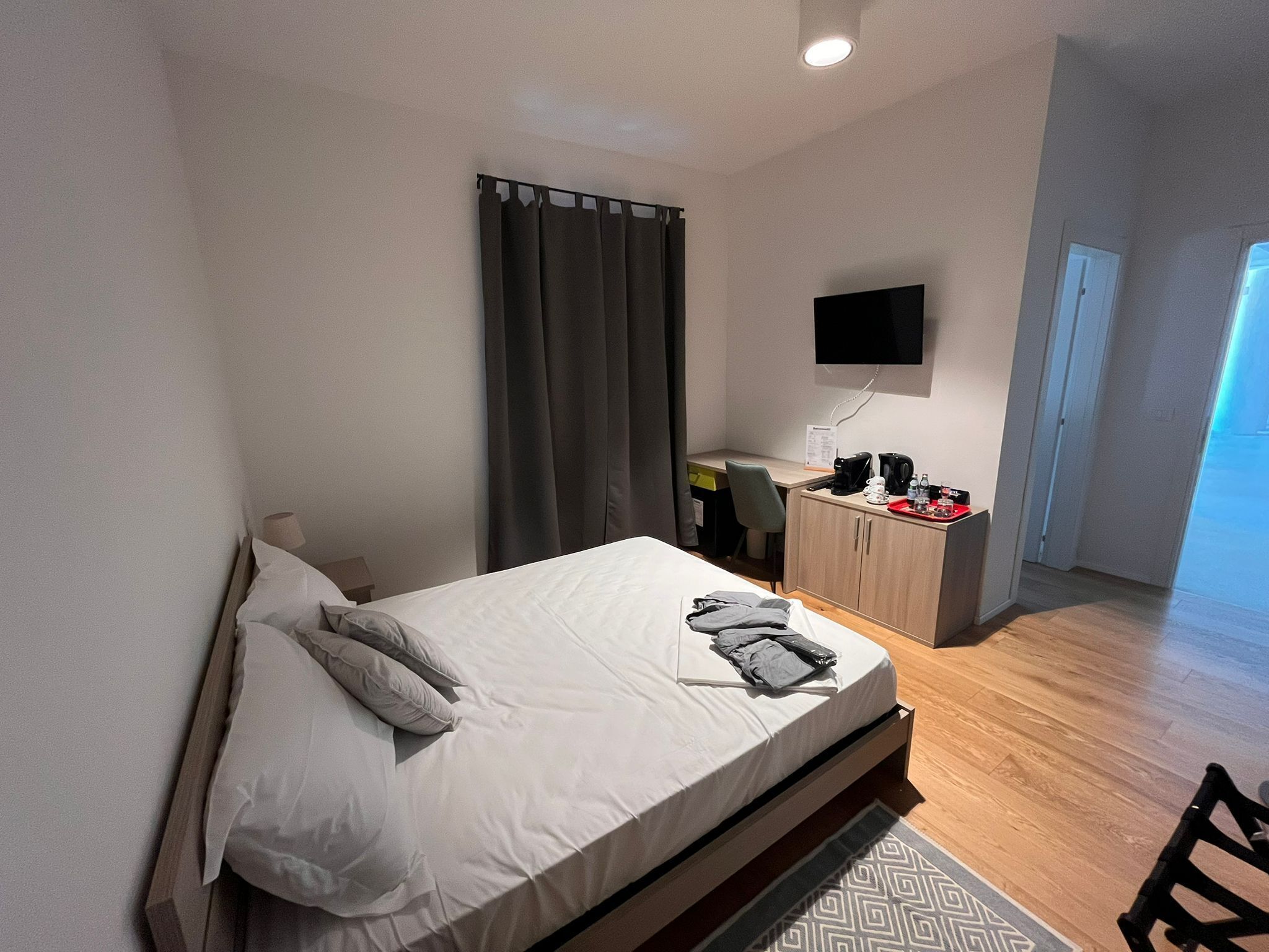 A hotel room with a bed, a desk, a TV, and a wardrobe.