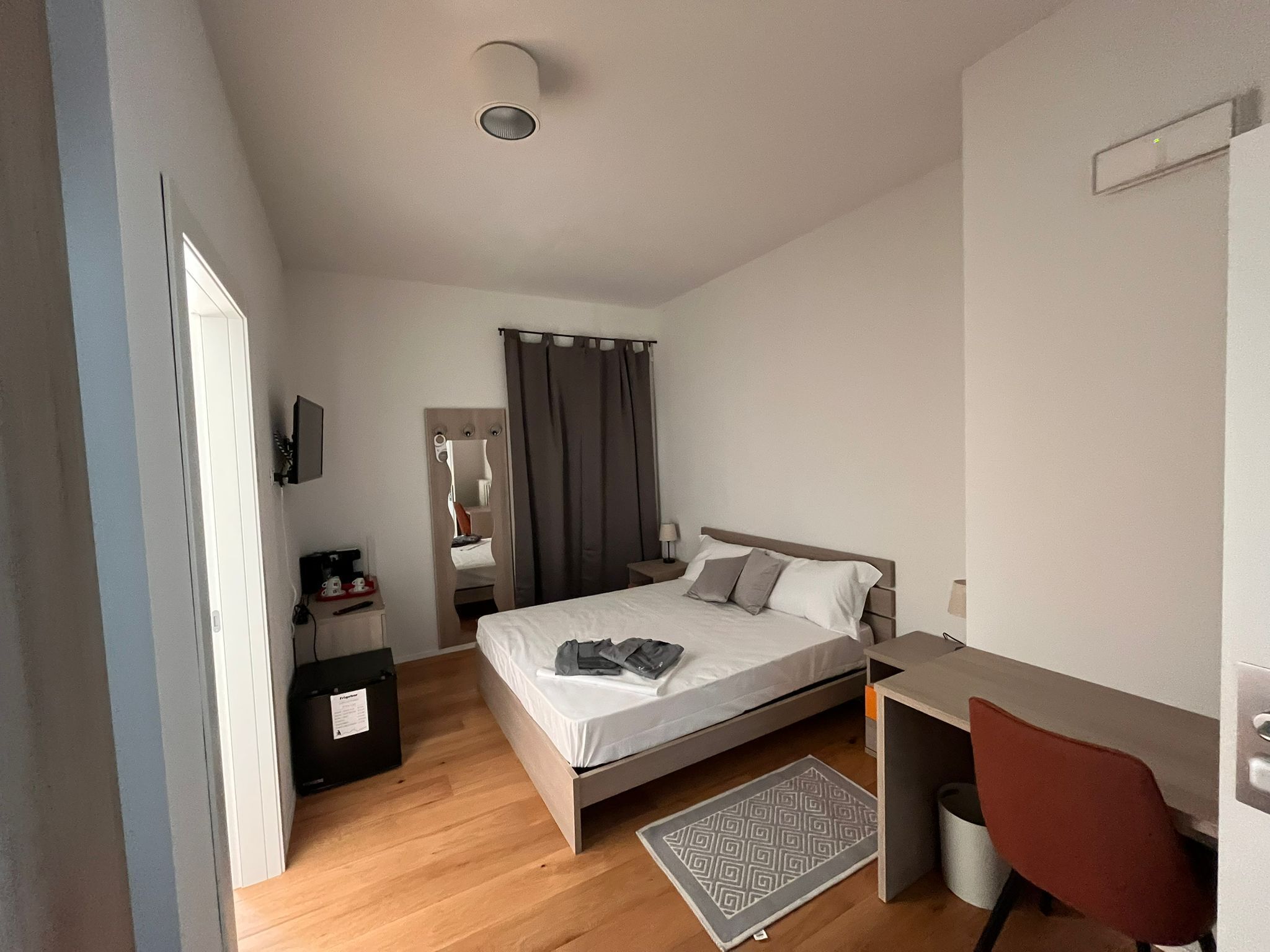 Un dormitorio moderno con cama, escritorio, silla y espejo.