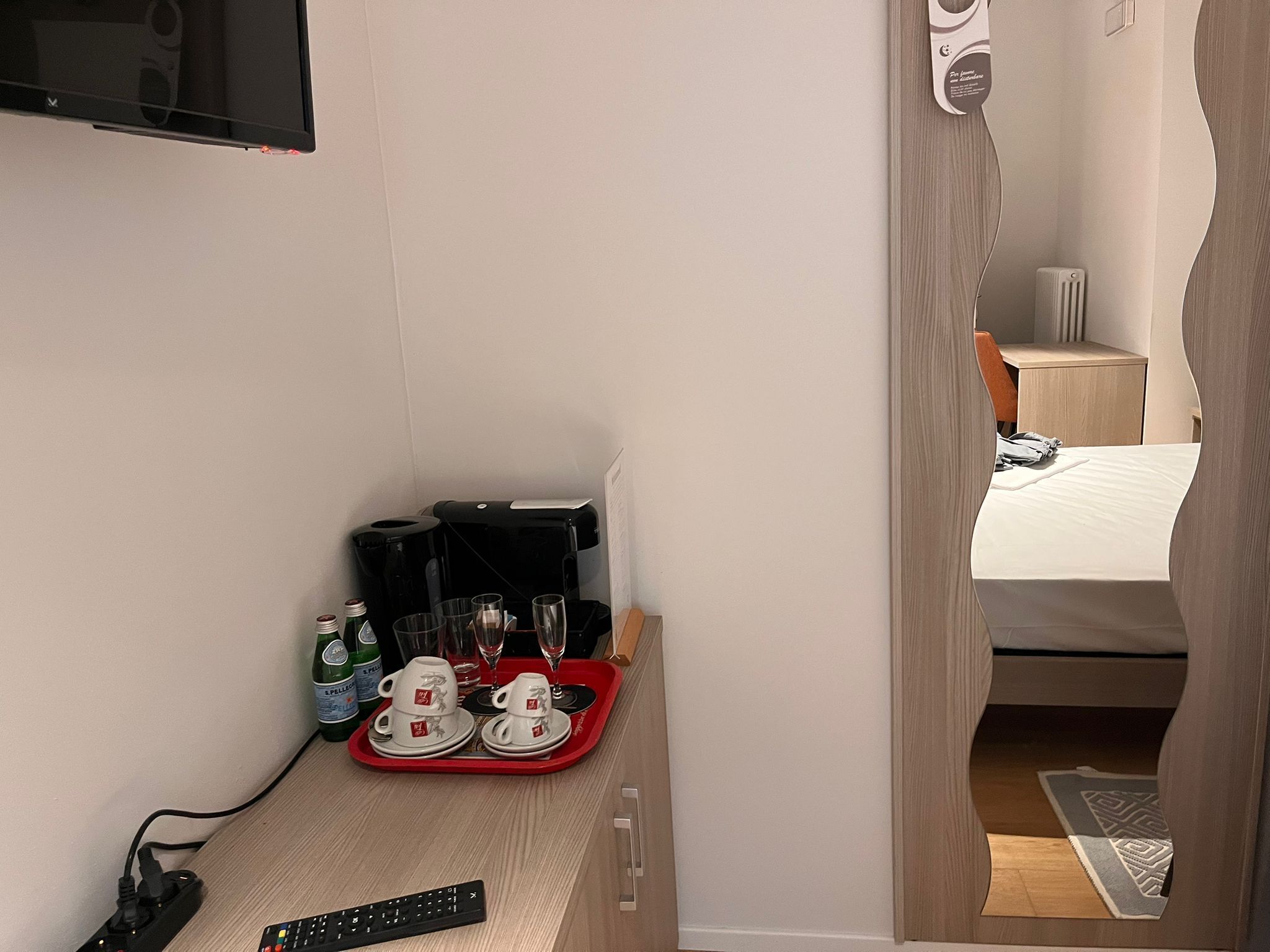 Een kleine kitchenette met een koffiezetapparaat, waterkoker en glazen op een dienblad.