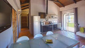 A modern kitchen with stainless steel appliances, a dining area with a glass table, and a cozy seating area with a white sofa. - 1 bedroom apartment in estã´mbar (Estômbar)