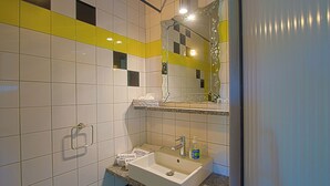 A bathroom with white and yellow tiles, a sink with a mirror, and a towel rack. - 1 bedroom apartment in estã´mbar (Estômbar)