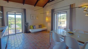A dining area with a table and chairs, a sofa with cushions, a fan, and a view of the outdoors through a glass door. - 1 bedroom apartment in estã´mbar (Estômbar)