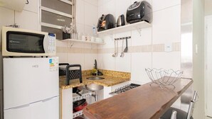Een kleine keuken met een magnetron, broodrooster en waterkoker aan de muur, een spoelbak en een houten aanrecht.