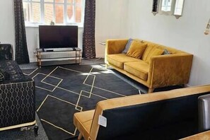 Relax in this stylish living room with a large flat-screen TV, comfortable sofa, and geometric rug.