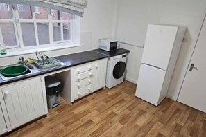 Compact kitchen with sink, washing machine, and refrigerator.