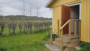 Un bâtiment jaune avec un escalier en bois menant à une porte, le tout entouré d’un vignoble.