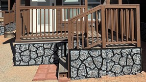 A lodge with a stone foundation, a wooden deck, and a staircase leading to the entrance.