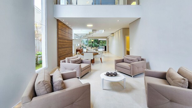 A spacious living area with sofas and a coffee table, a dining area in the background, and a view of the outdoors. - Casa Riviera 292 (Bertioga)