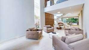 A spacious living area with modern furniture, a dining area, and a staircase leading to an upper level. - Casa Riviera 292 (Bertioga)
