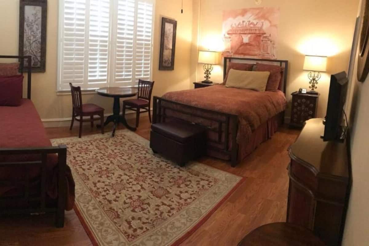 Un dormitorio con una cama, un escritorio, una silla y una mesita.