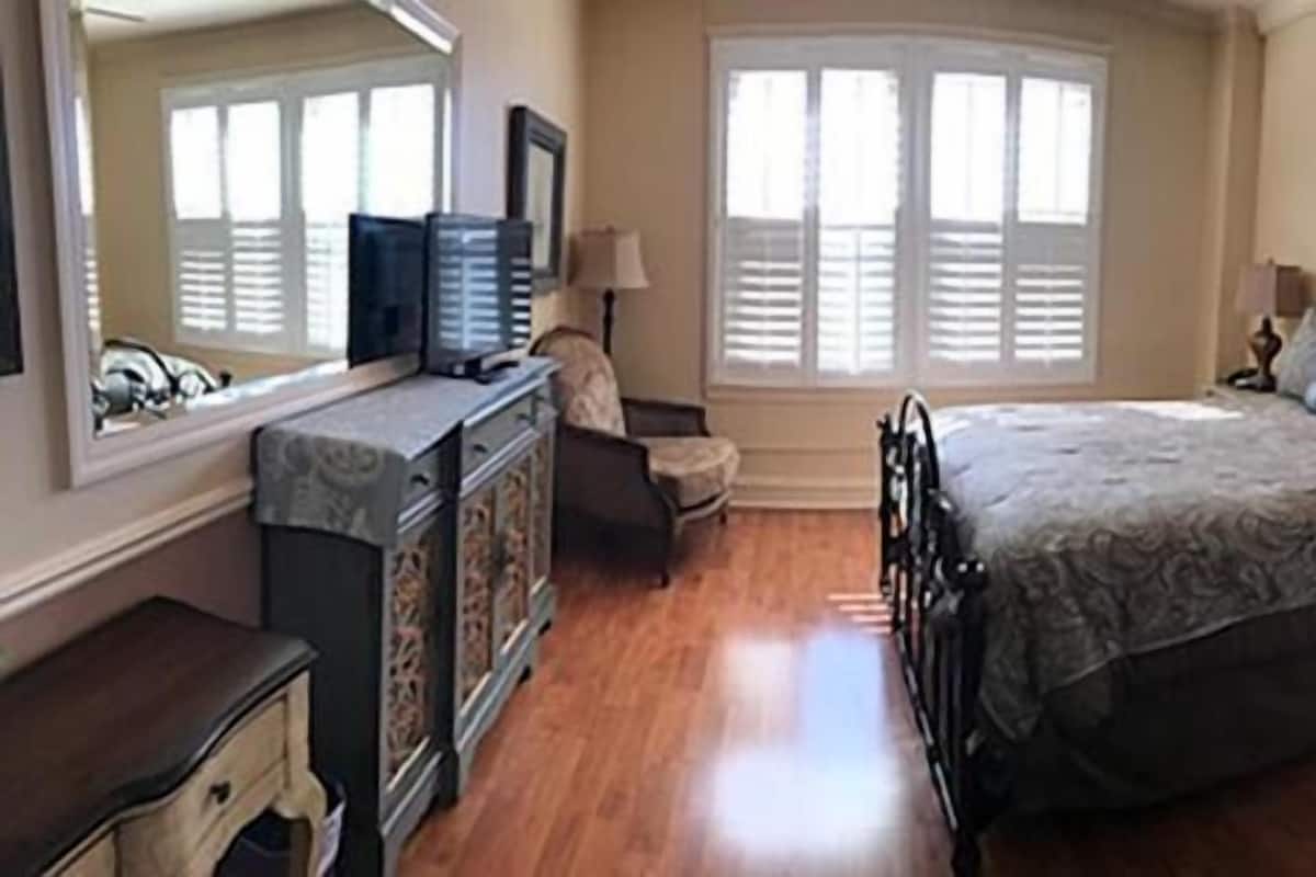 Un dormitorio con cama, cómoda, silla, mesa y ventana con persianas.