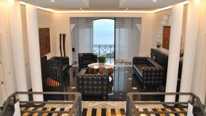 A spacious living area with a high ceiling, a central seating arrangement, and a view through a glass door to the outside. - B&B Villa La Ventana (Sant'Agnello)