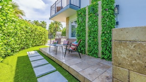 Une maison moderne dotée d’un balcon, d’une terrasse avec mobilier d’extérieur et d’un jardin bien entretenu.