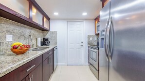 Une cuisine dotée de plans de travail en granit, d’appareils électroménagers en acier inoxydable et d’armoires en bois.