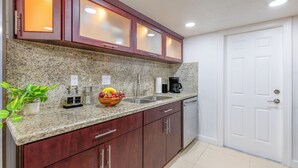 Une cuisine dotée de plans de travail en granit, d’armoires en bois, d’un four encastré et d’une porte blanche.