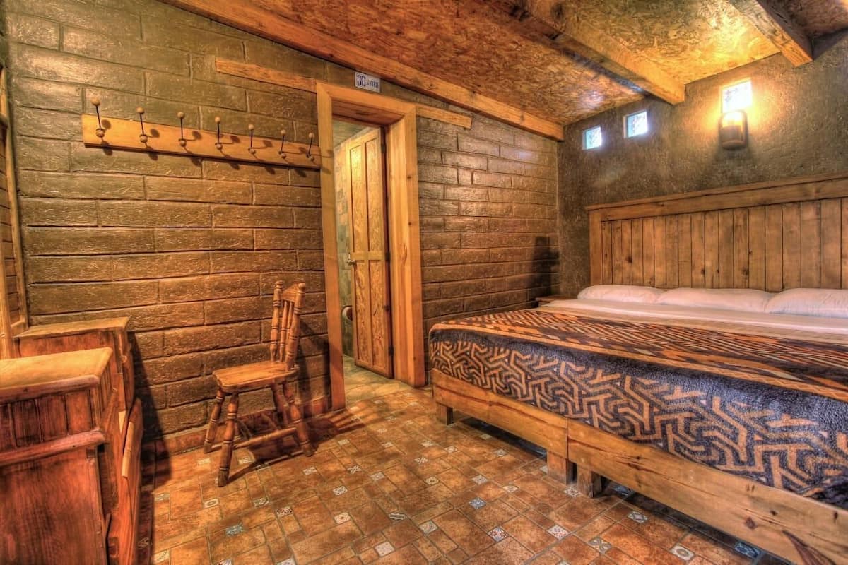 Una habitación rústica de madera con una cama, un banco de madera y una silla.