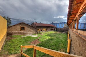 A rustic courtyard with wooden buildings, a grassy area, and a wooden bench. - Hotel Finca Belen  (Tlaxco)