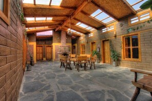 A rustic wooden building with a stone floor, wooden furniture, and a brick fireplace. - Hotel Finca Belen  (Tlaxco)