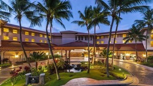 Un hotel con un patio central, palmeras y un pequeño elemento acuático.