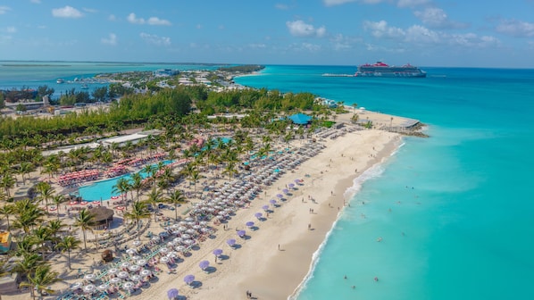 A resort with a large pool, beach, and ocean view.