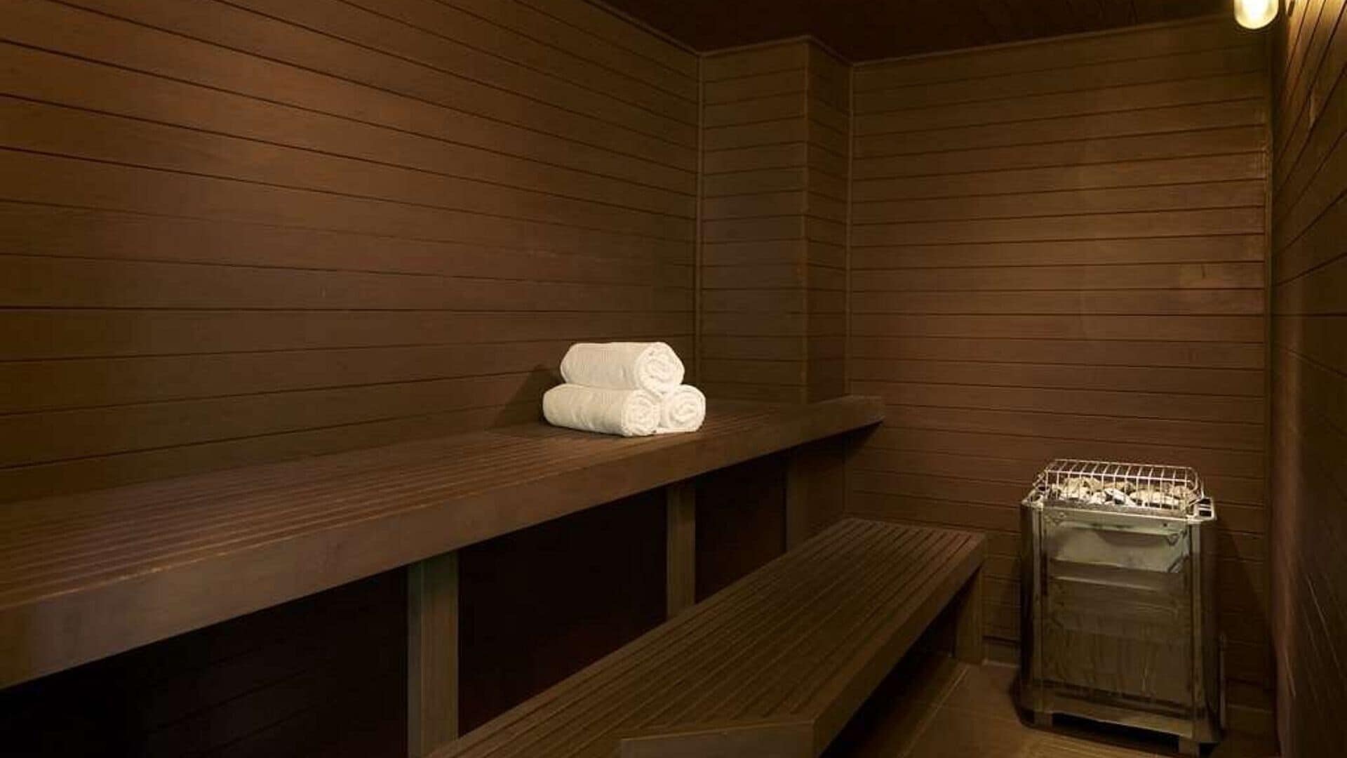 A wooden sauna with benches and a towel rack.