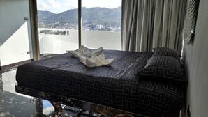 A hotel room with a bed, a view of a cityscape, and a balcony. - Spacious 4-bedroom apartment with WiFi, AC in fantastic LUXURY (Tambon Patong)