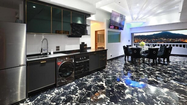 A modern kitchen with a black and white marble floor, stainless steel appliances, and a dining area with a table and chairs. - Spacious 4-bedroom apartment with WiFi, AC in fantastic LUXURY (Tambon Patong)