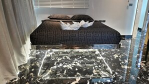 A bedroom with a bed, patterned pillows, and a marble floor. - Spacious 4-bedroom apartment with WiFi, AC in fantastic LUXURY (Tambon Patong)