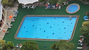 A large rectangular swimming pool with a diving board, surrounded by lounge chairs and umbrellas. - Spacious 4-bedroom apartment with WiFi, AC in fantastic LUXURY (Tambon Patong)