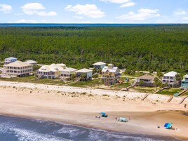 Une zone résidentielle côtière comprenant plusieurs maisons, une plage et une zone boisée en arrière-plan.