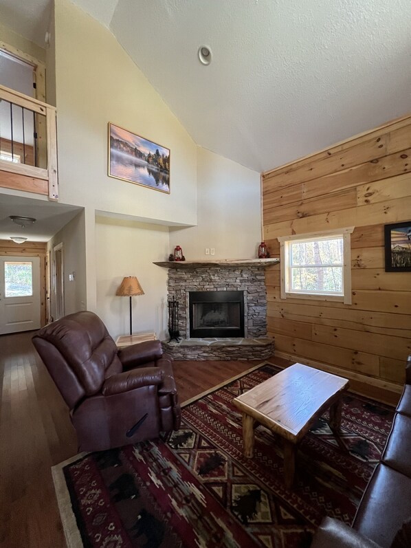 A cozy living room with a stone fireplace, leather sofa, and a wooden ceiling. - Little Bear (Topton)