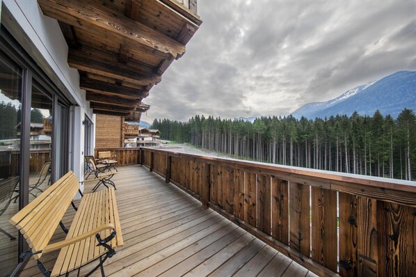 Una terraza de madera con bancos, con vistas a un bosque y montañas.