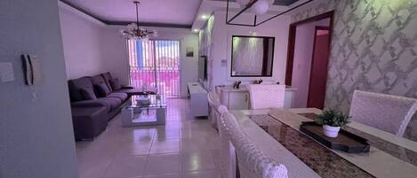 A modern living room with a sofa, coffee table, and a dining area with a bench and table.