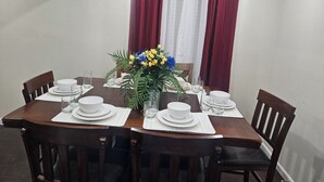 Ein Esstisch für sechs Personen, gedeckt mit weißen Tellern, Gläsern und einer Blumendekoration aus gelben und blauen Blumen.
