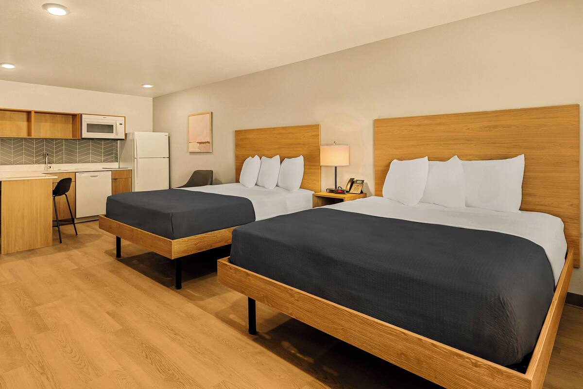 Ein Hotelzimmer mit zwei Betten, einer Küchenzeile und einem kleinen Schreibtisch.