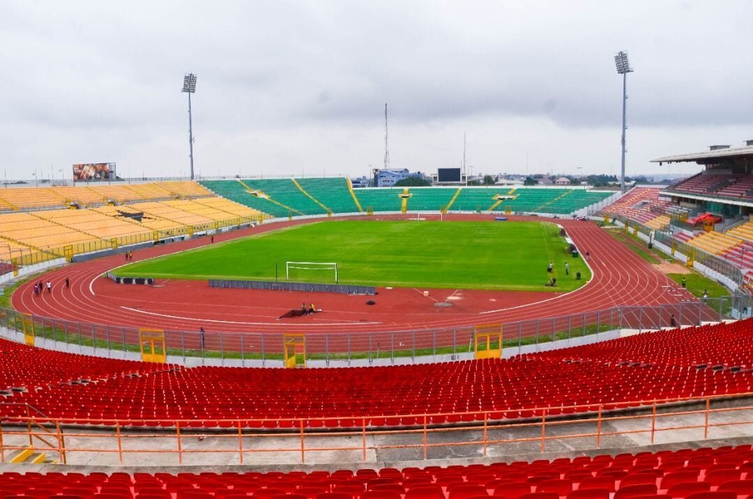 A stadium with multiple seating sections, a running track, and a green field.