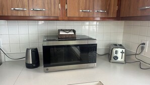 A kitchen with wooden cabinets, a microwave, a toaster, and a kettle on the counter. - Charming Vacation Home Near Niagara Falls & Highmark Stadium (Depew)