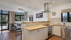 A modern kitchen with a built-in oven, a dishwasher, and a large window overlooking a scenic landscape.