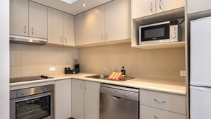 A modern kitchen with stainless steel appliances, including a Bosch dishwasher and oven, and a microwave above the sink. - Lantern 24 Balcony (Thredbo)