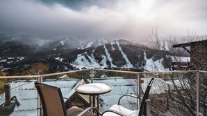 A glass-enclosed terrace with a view of snow-covered mountains and a chair. - Lantern 12 Balcony - views from every window (Thredbo)