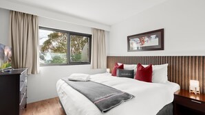 A modern hotel room with a large bed, a desk, and a window with curtains.