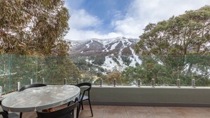 An outdoor seating area with a table and chairs, overlooking a snow-covered mountain range.