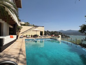 A pool area with a view of a mountain and a body of water.