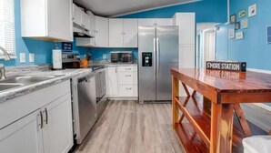 A modern kitchen with white cabinets, stainless steel appliances, and a wooden table with a sign.