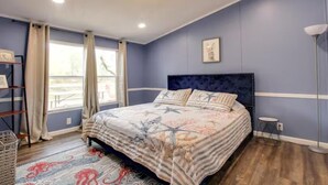 A bedroom with a bed, a window, a floor lamp, and a bedside table.