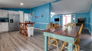A spacious kitchen with white cabinets, a wooden dining table, and chairs.