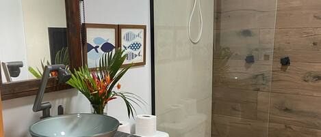 Un baño moderno con cabina de ducha de vidrio, lavabo sobre encimera y un inodoro.