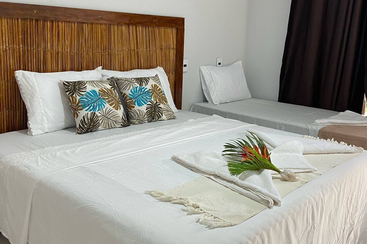 A hotel room with a large bed, a smaller bed, and a wooden headboard.