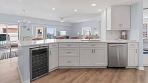 A modern kitchen with white cabinets, a built-in oven, and a dishwasher. - Oceanwalk 1-605 (New Smyrna Beach)